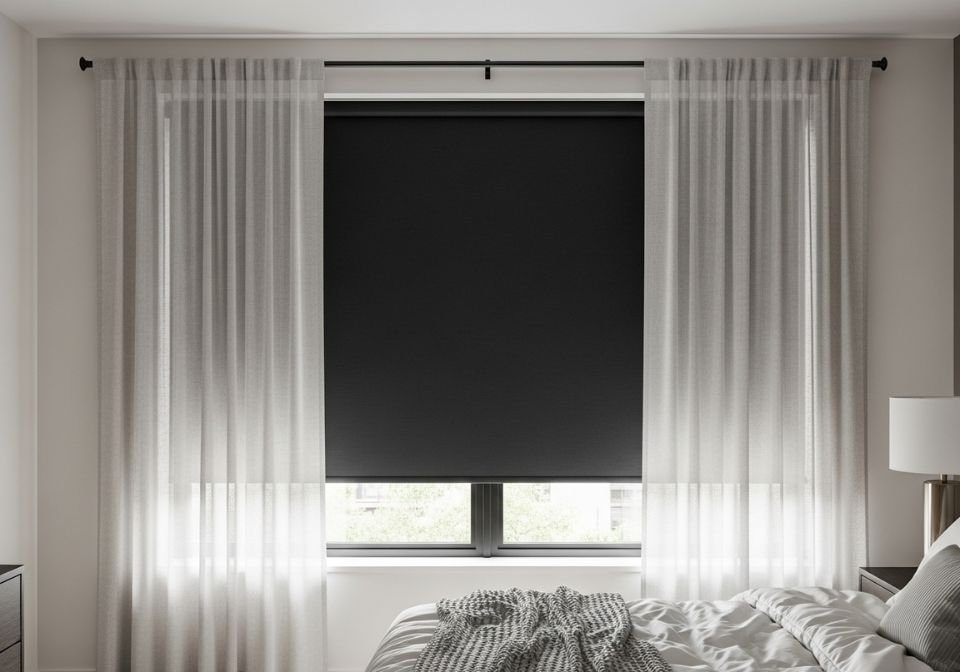 Bedroom window with blackout shade and soft sheer curtains.
